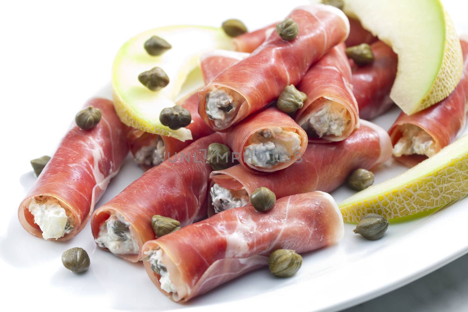 Parma ham rolls filled with cream cheese, Galia melon and capers