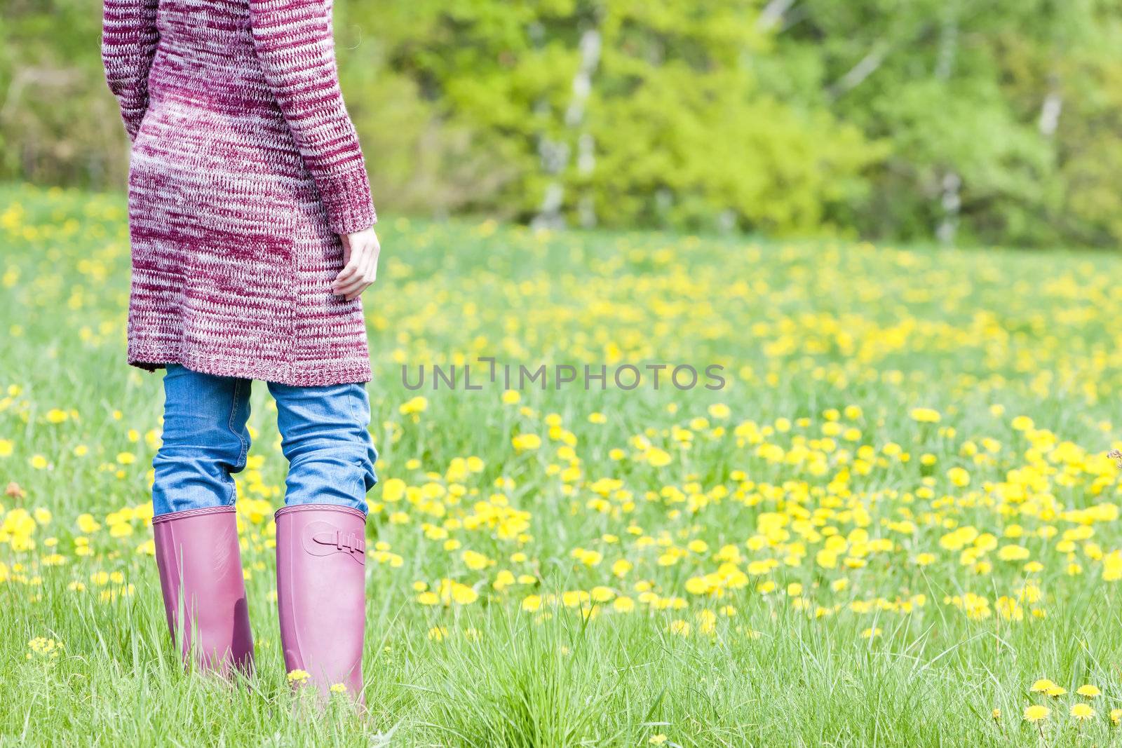 detail of woman wearing rubber boots on spring meadow