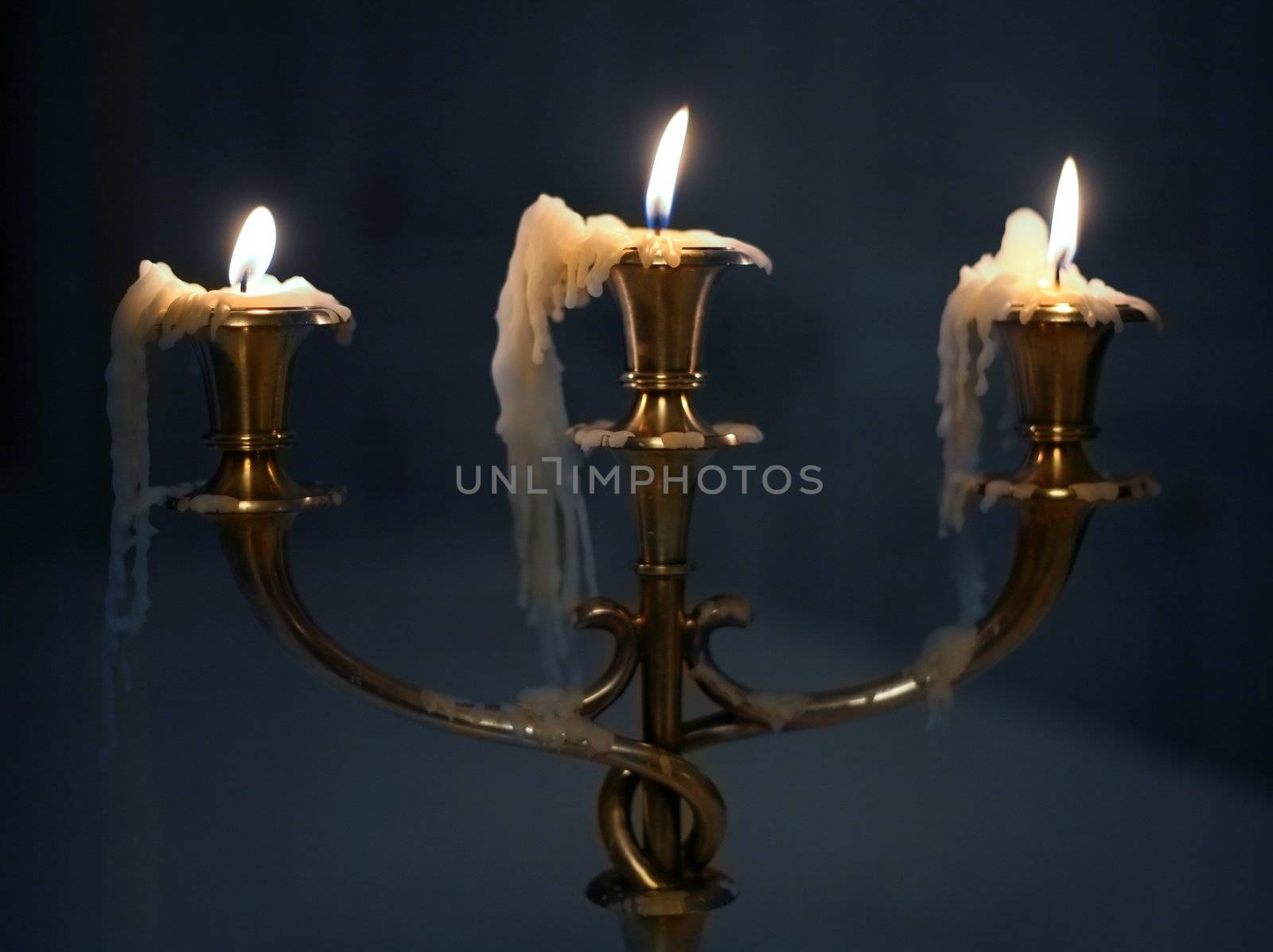 Three burning candles in an ancient gold candelabrum