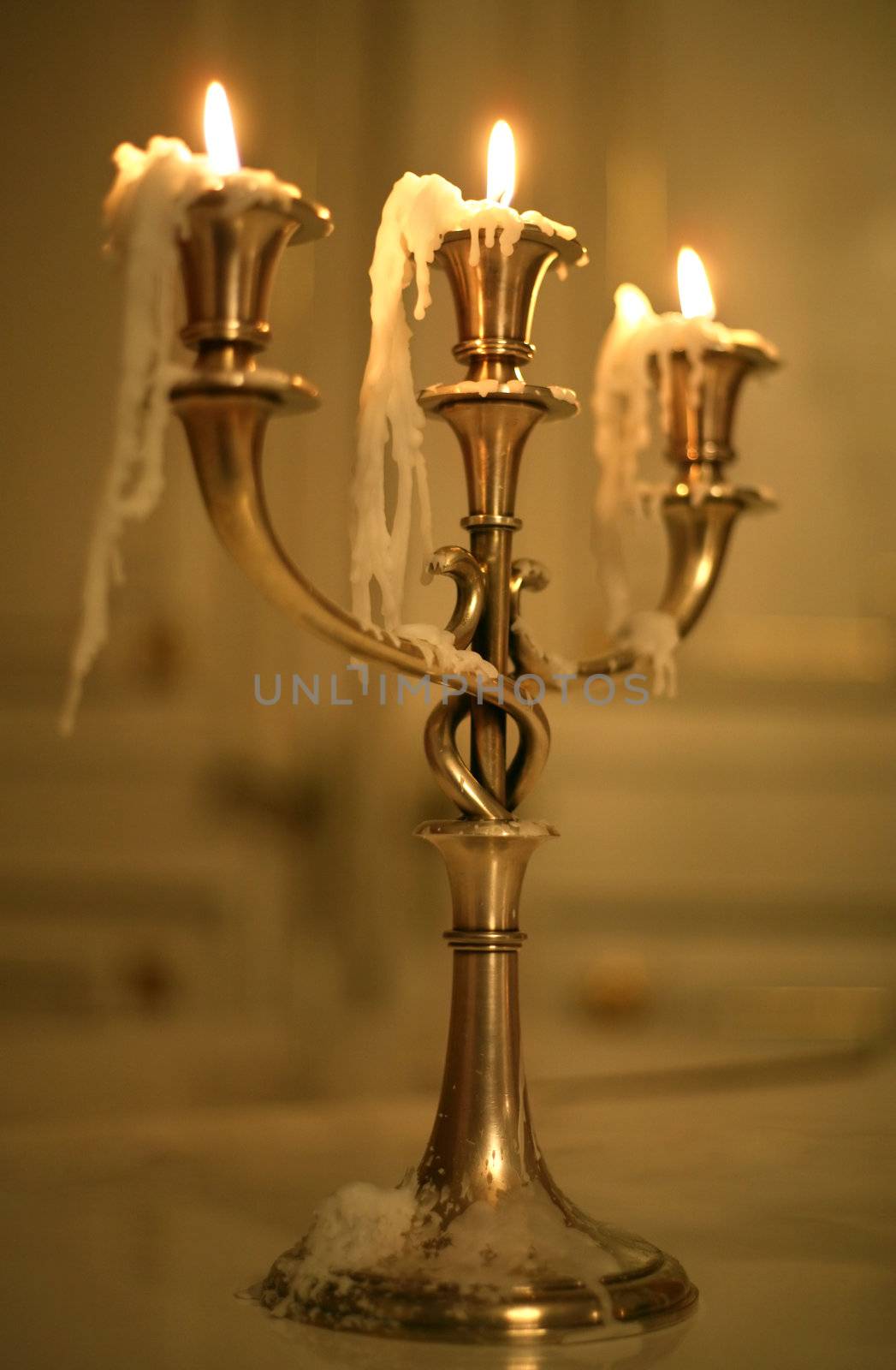 Three burning candles in an ancient gold candelabrum