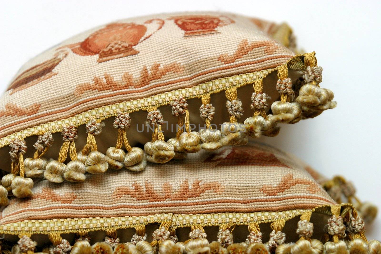 Two pillows with pompons lay one on another