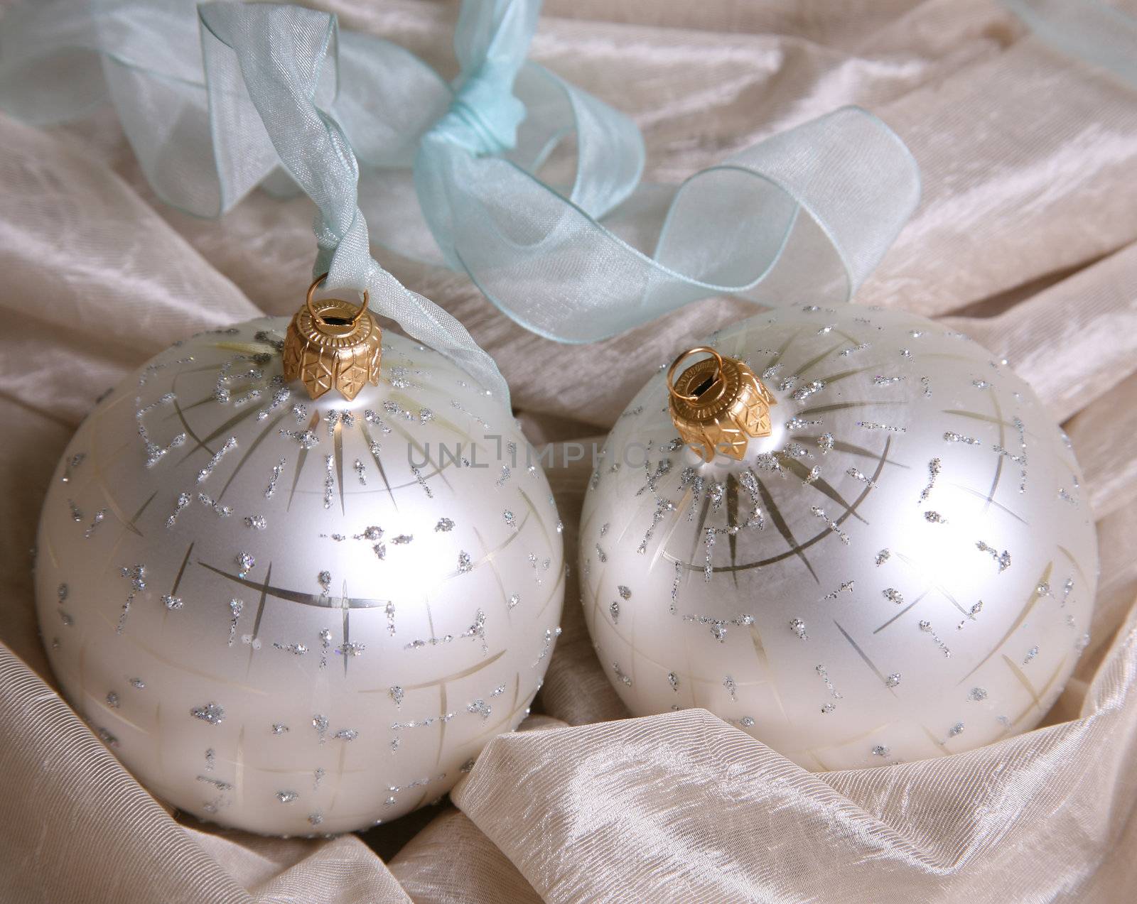 Two christmas spheres on a pink fabric
