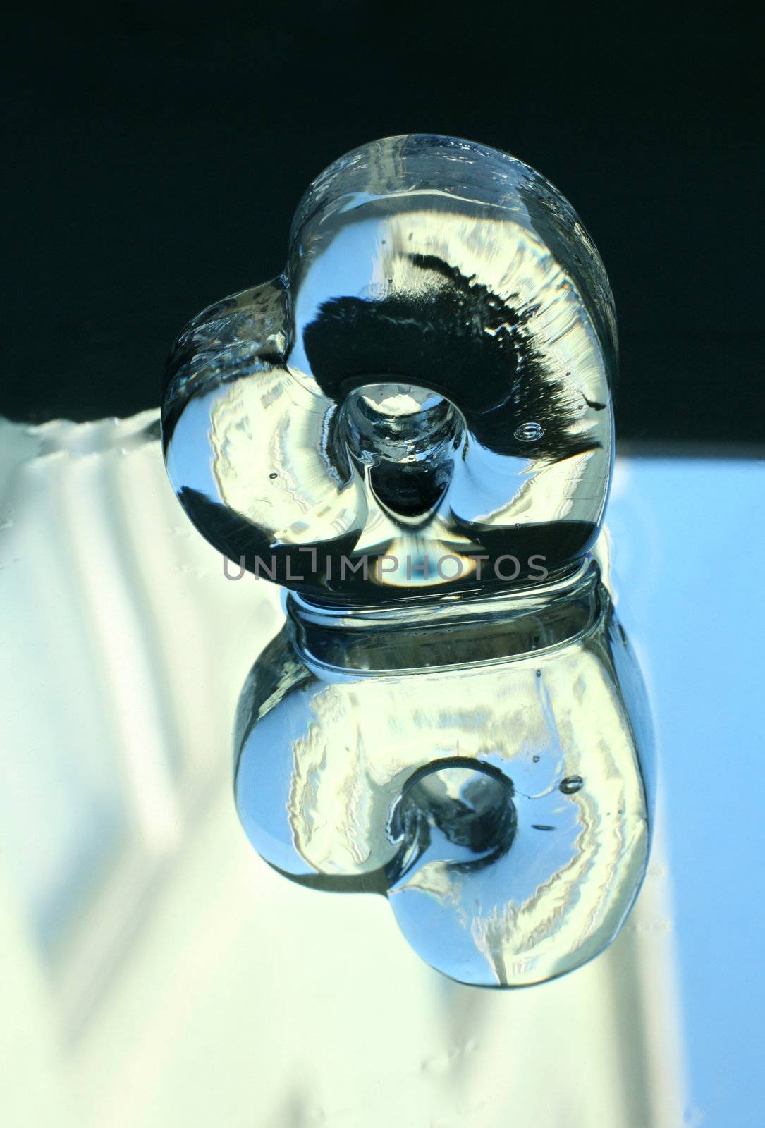 The image of glass heart with reflection in a smooth surface