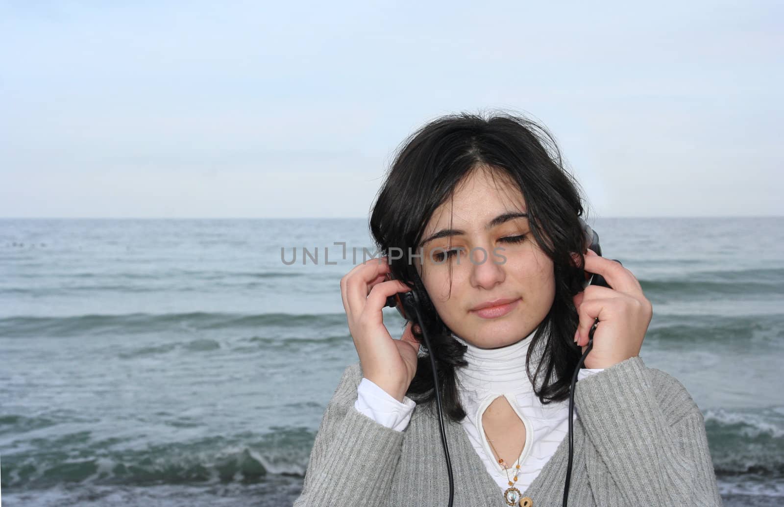 The girl has closed eyes and hears the sea