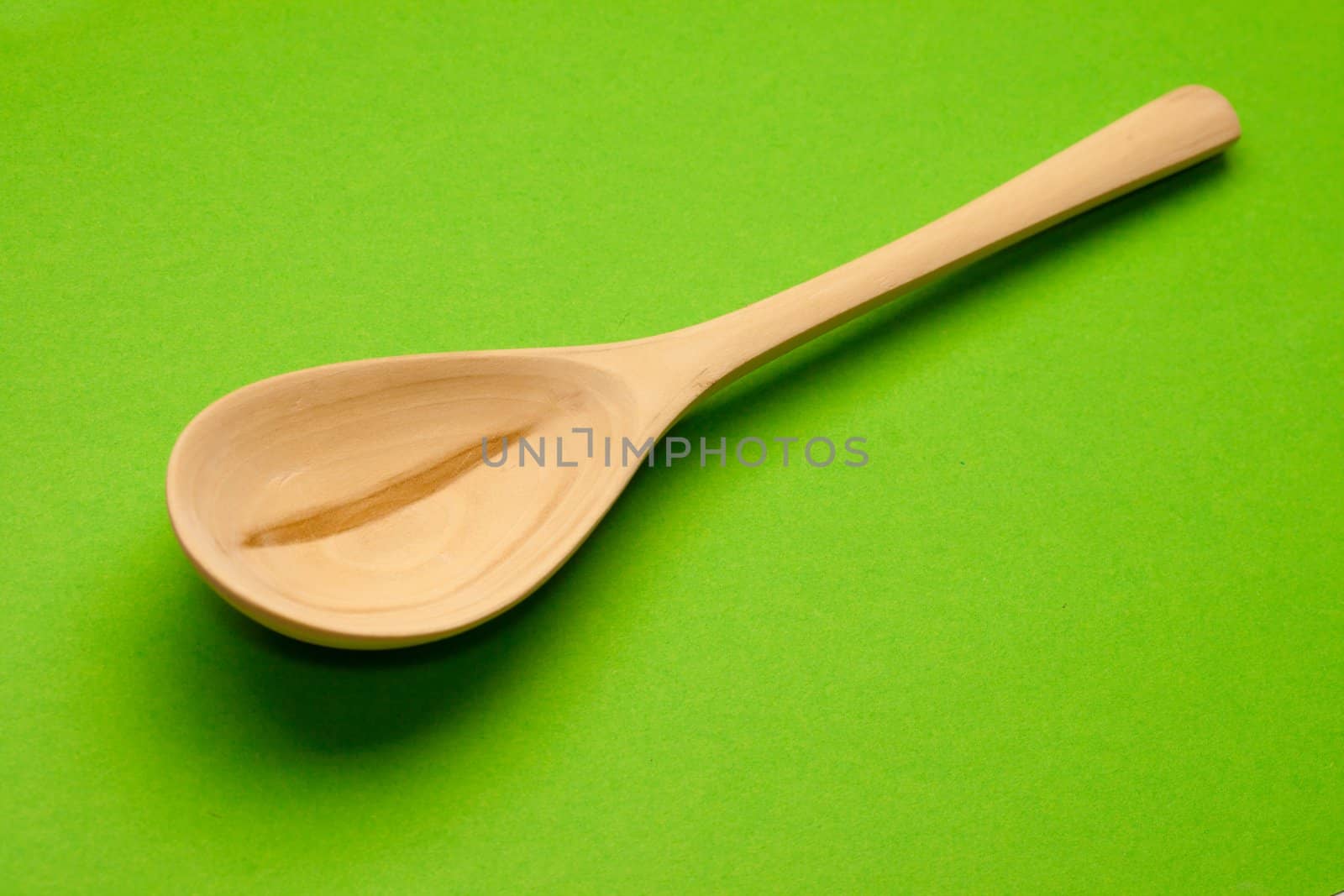 Wooden spoon isolated on green background