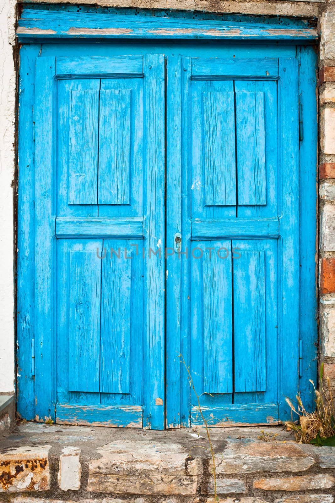 Old weathered blue door in a house in Greece