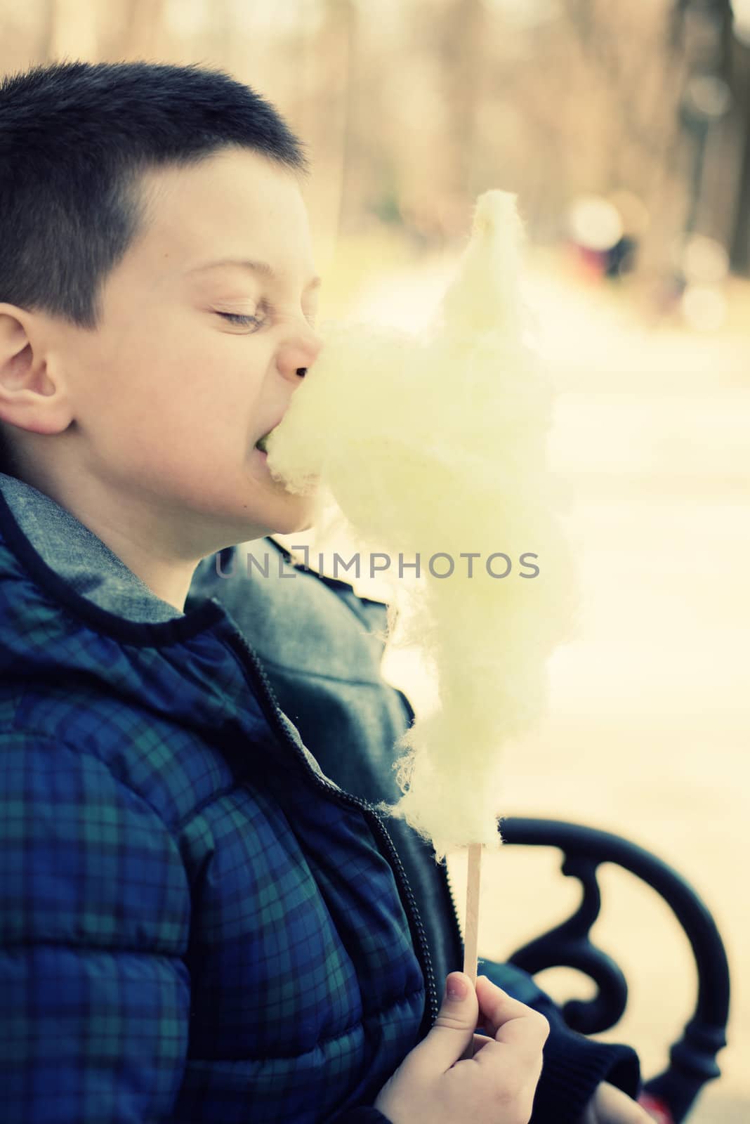 Boy bitting a sugarwool chunk in a sunny park