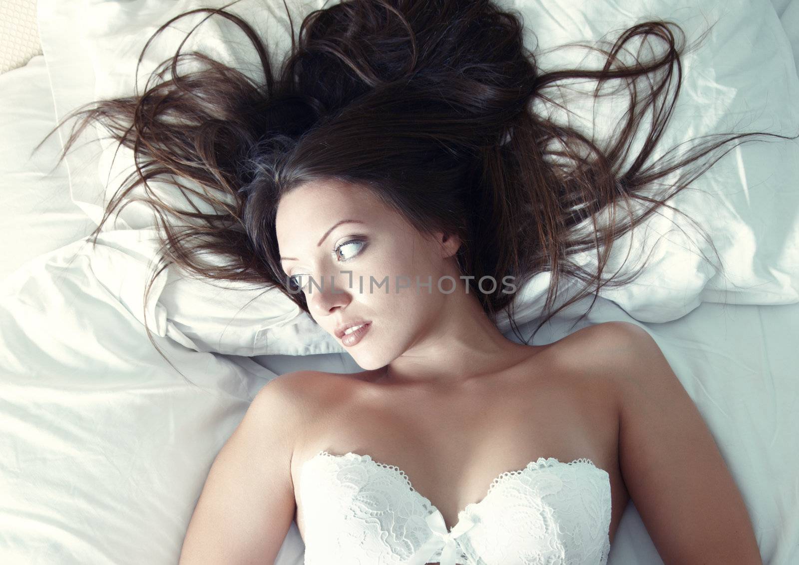 Pretty lady in camisole lays on the bed. Natural light and colors