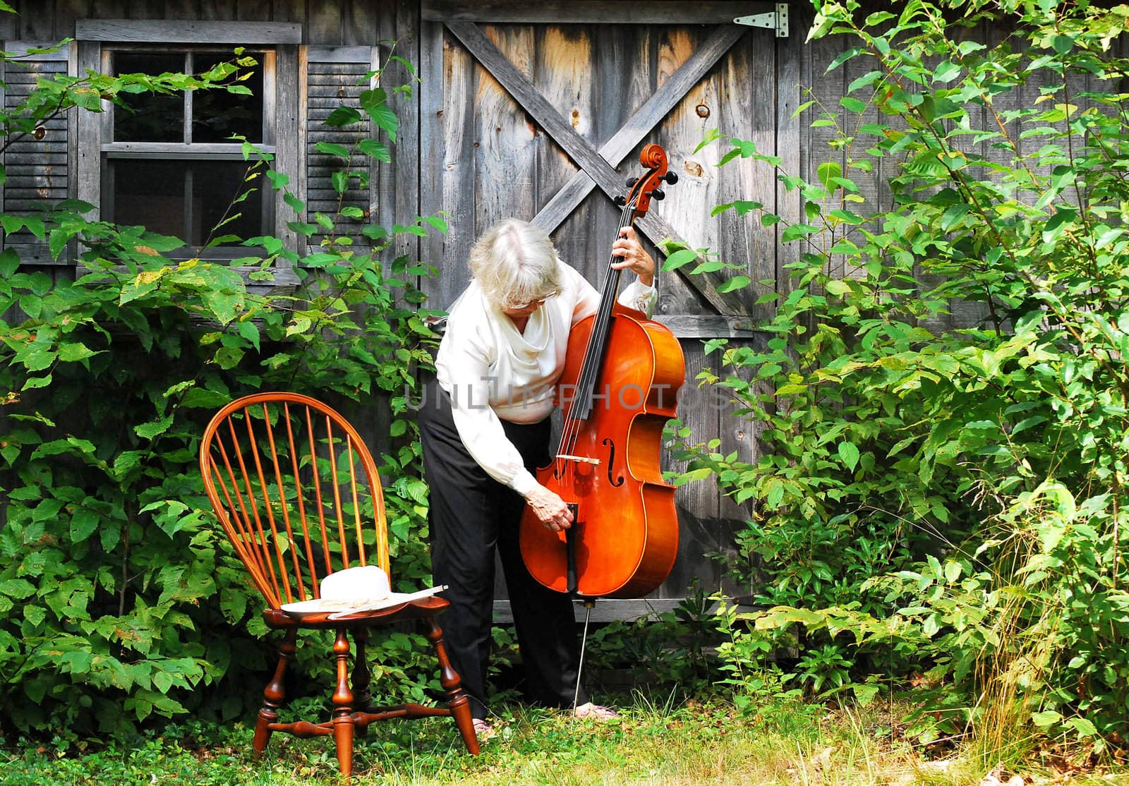 Female cellist standing with her cello outside.