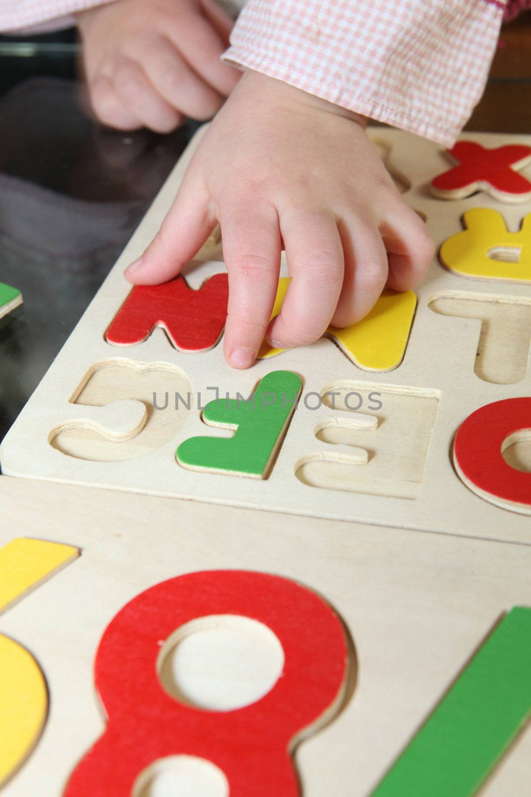 Little kid playing with letter puzzle