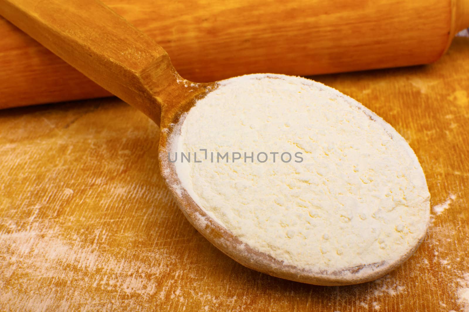 Whole flour in spoon on rustic wooden background
