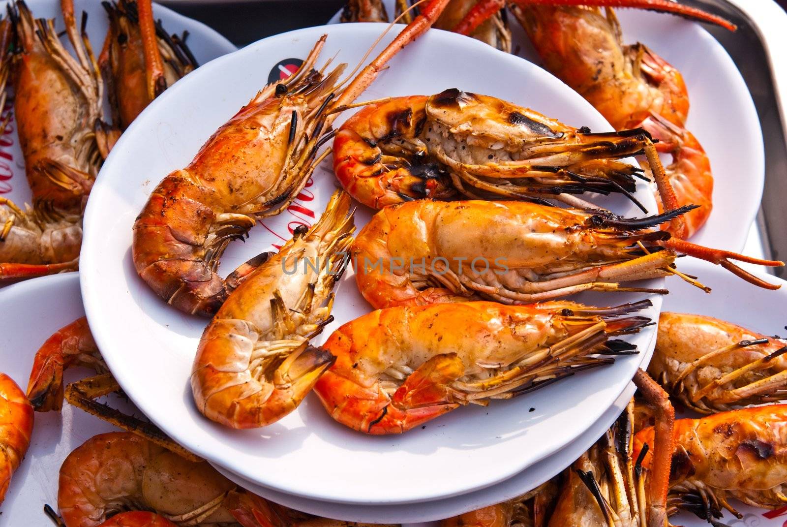 Flame grilled large prawns on white plates, use for seafood, health and wellness related concepts
