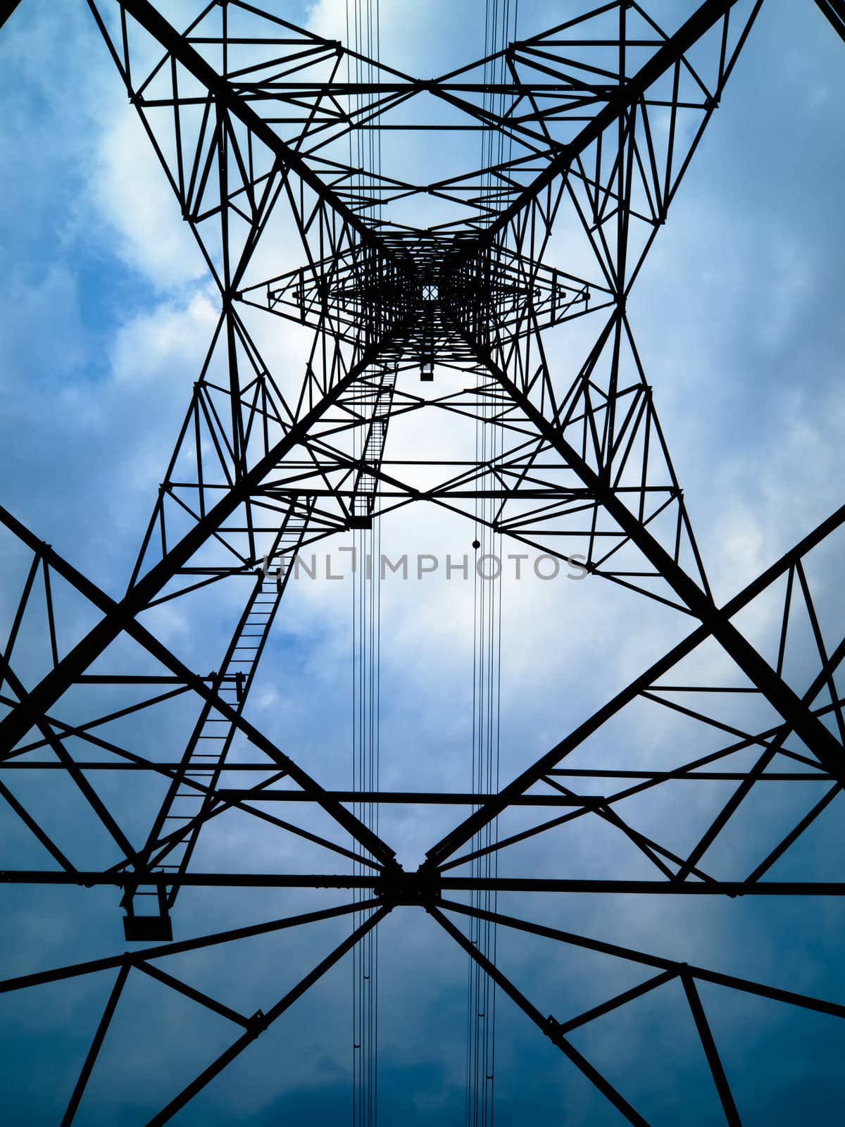 Under Silhouette of high voltage tower and overcast sky