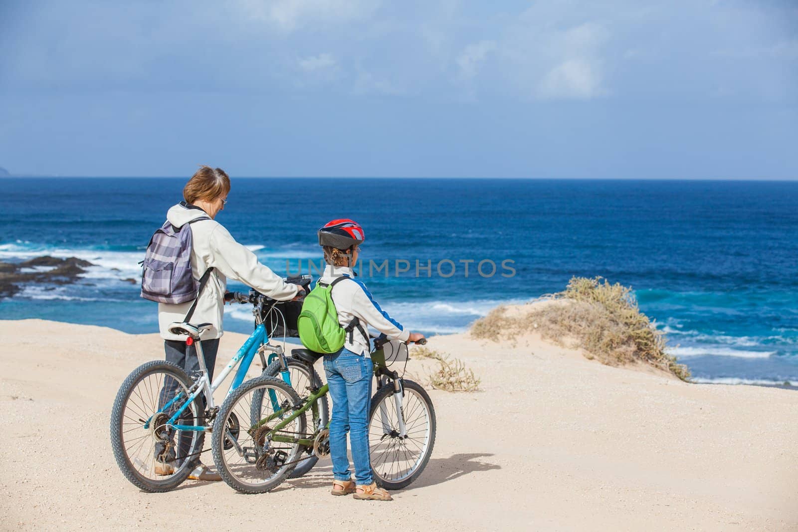 Beautiful girl and her grandmother on bikes on the beach. Lanzarote