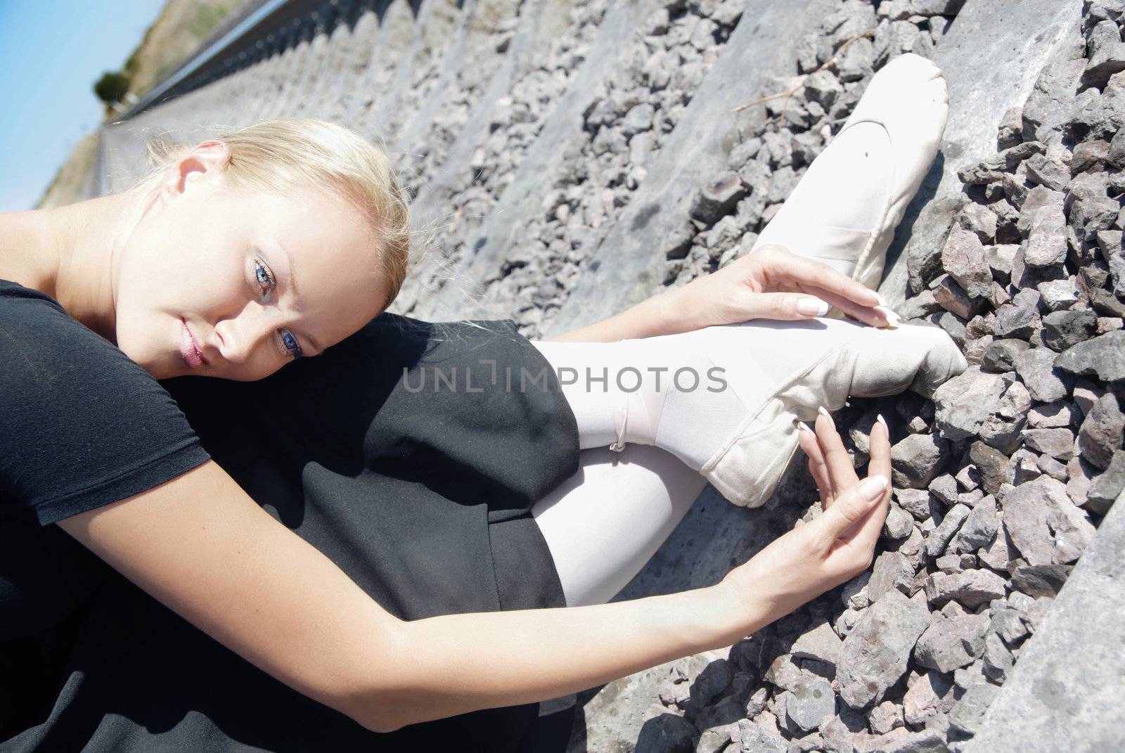 Tired woman sitting on the railway in ballet clothes