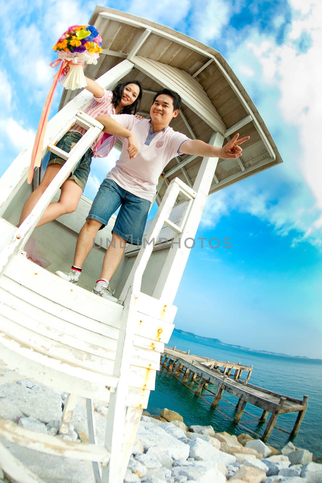 couple standing on tower on the beach with beautiful flowers bouquet