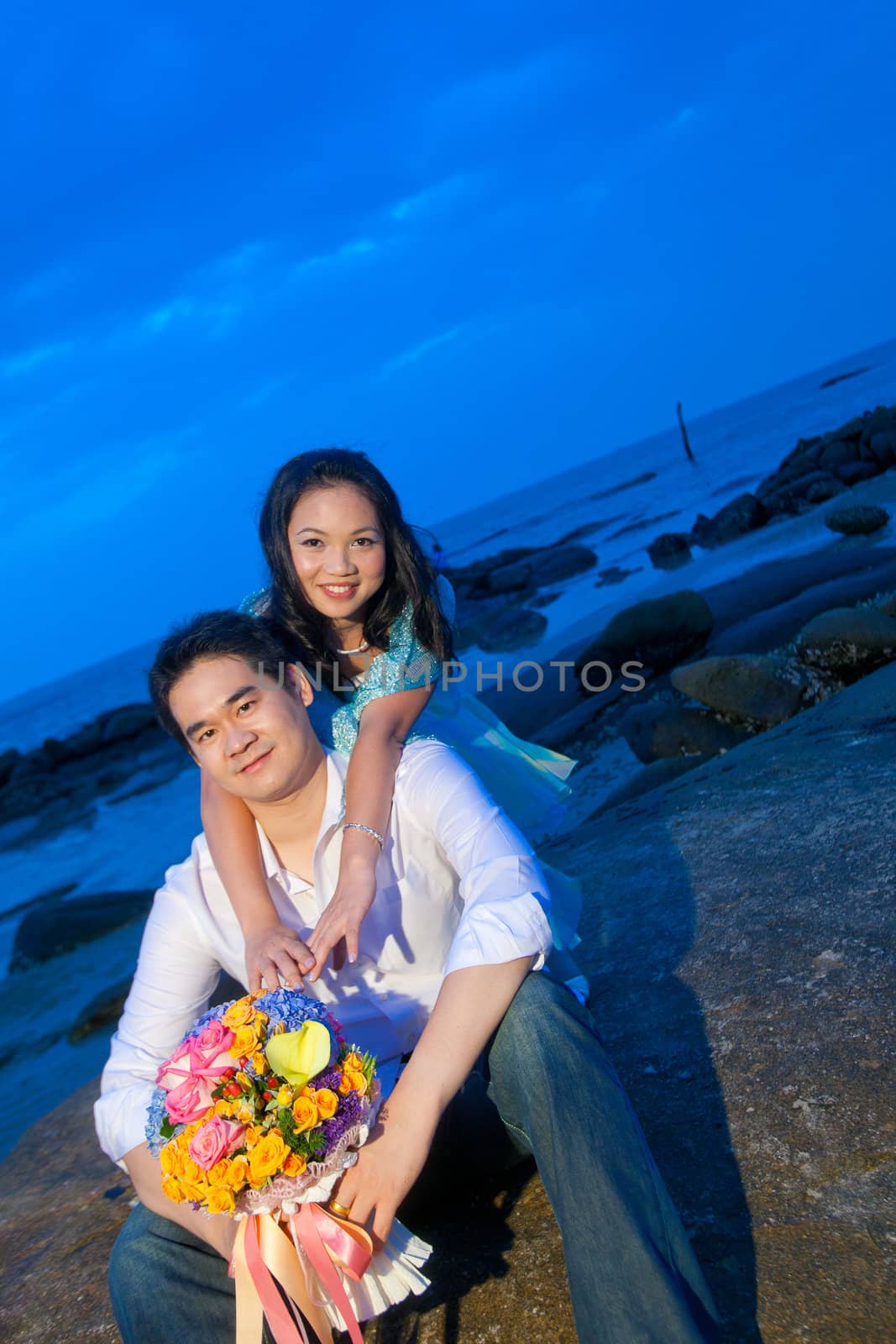 attractive young girl embracing her handsome boyfriend on the beach at dusk