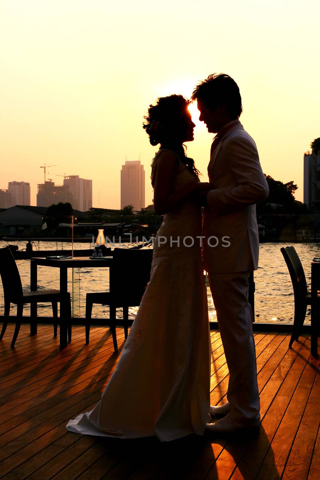 Silhouette of Bride and Groom kissing on the romantic wedding along Chaophraya River , bangkok Thailand