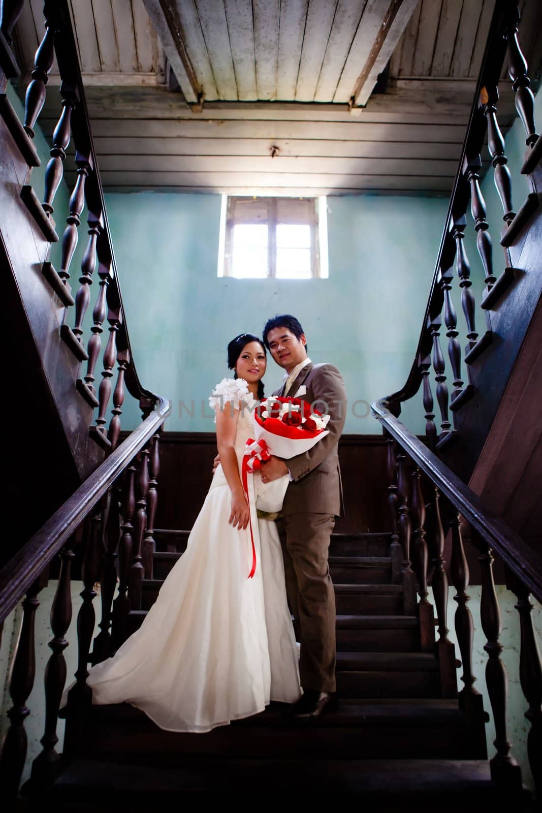 Bride and groom standing at ladder indoor of old building
