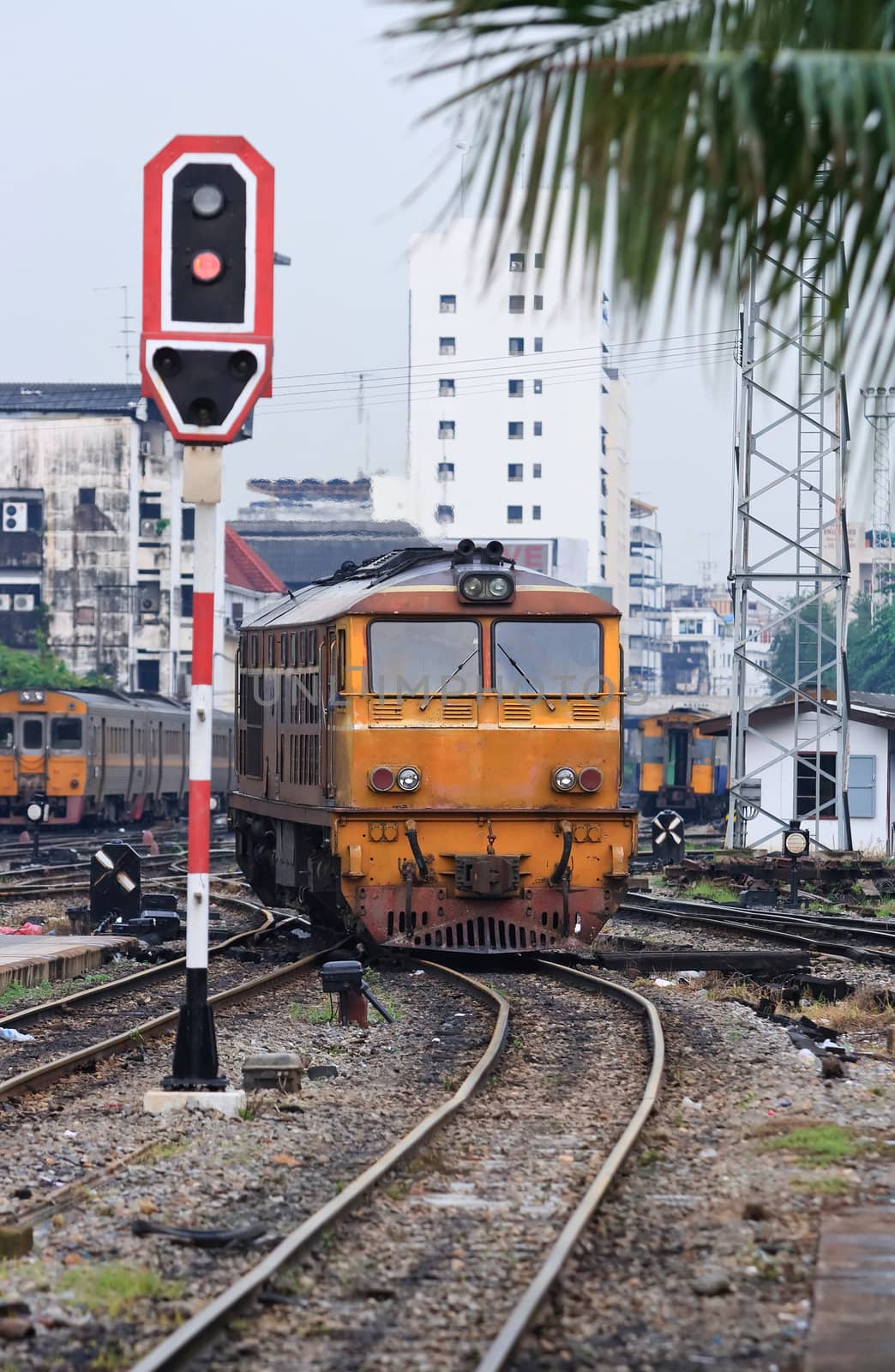 Orange Train locomotive approaching to Bangkok Railway Station Thailand with Red Train Signals