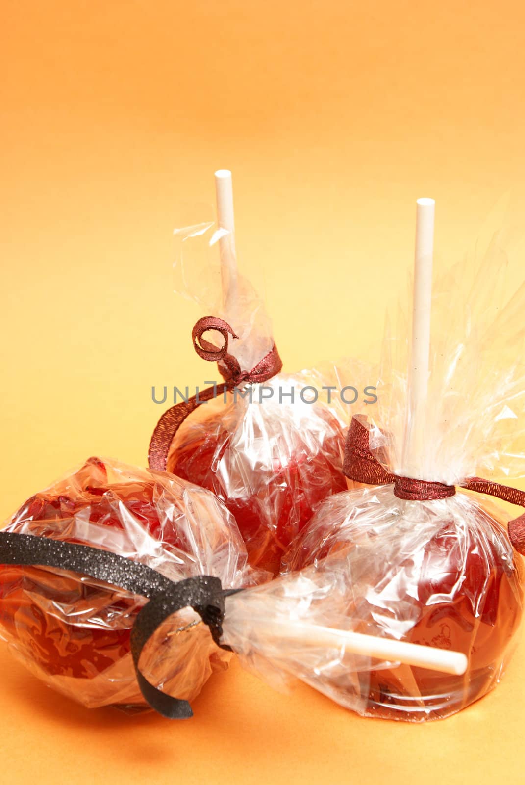 Three red candy apples in plastic wrappers ready for treating the sweet tooth.
