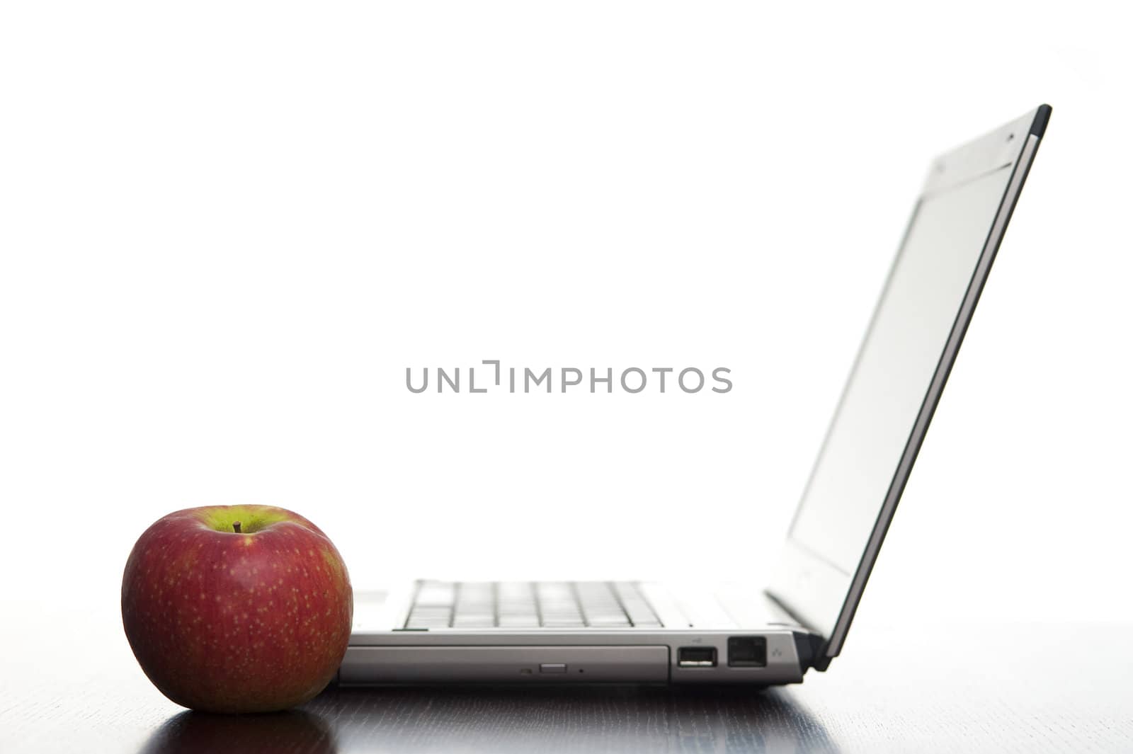 Open laptop sideways on with a fresh red apple in an education concept.