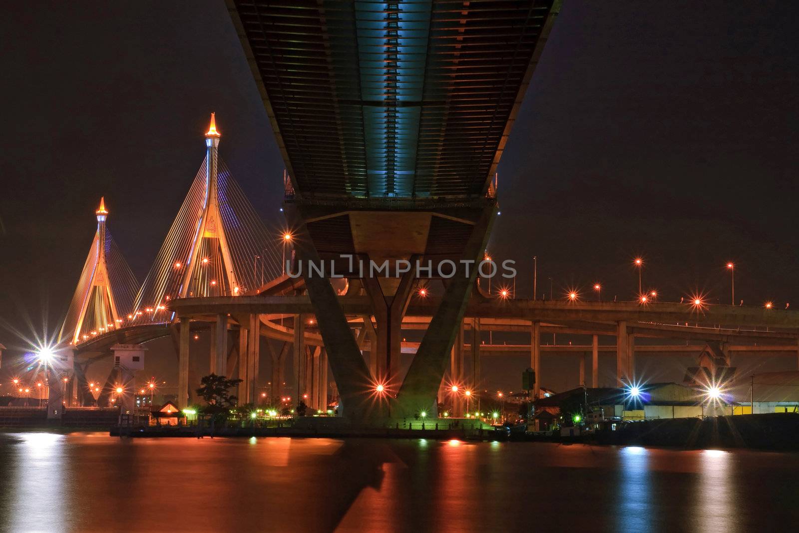 The Industrial Ring Bridge shines at dusk in Thailand with central perspective. The Bridge cross over ChaoPhraya River and Bangkok Harbor