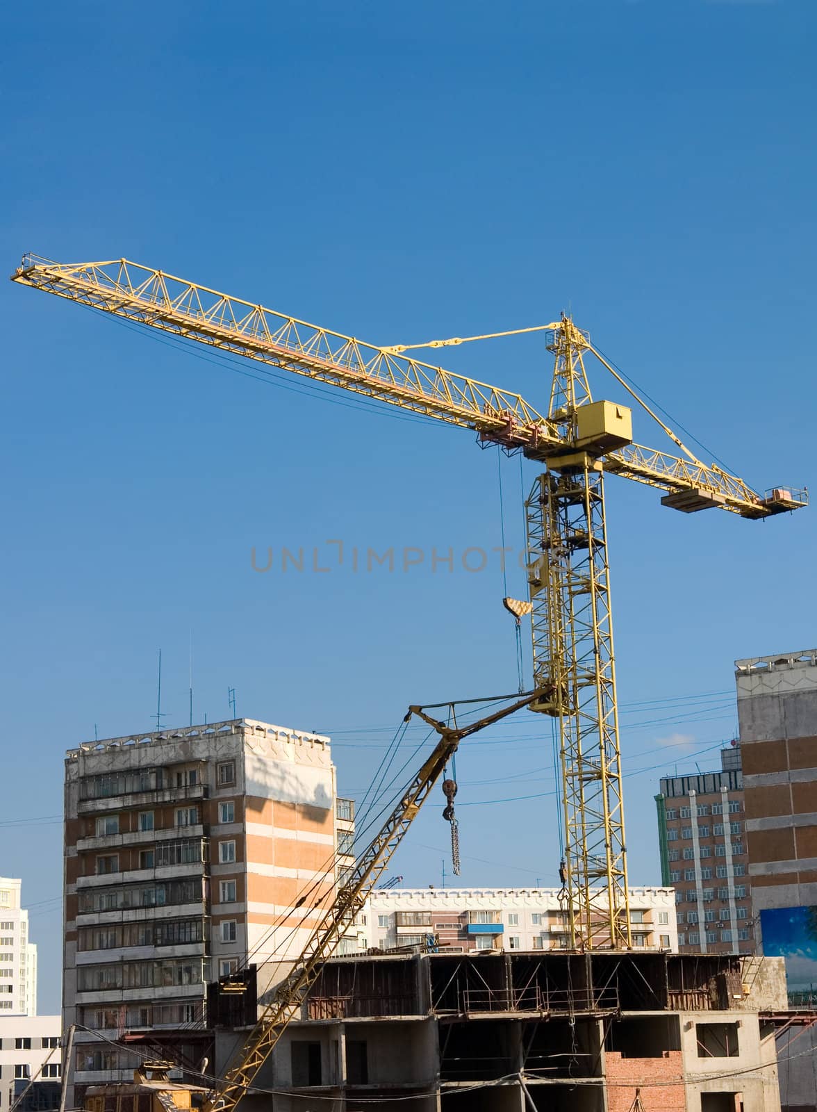 The tower crane on a background of the blue sky