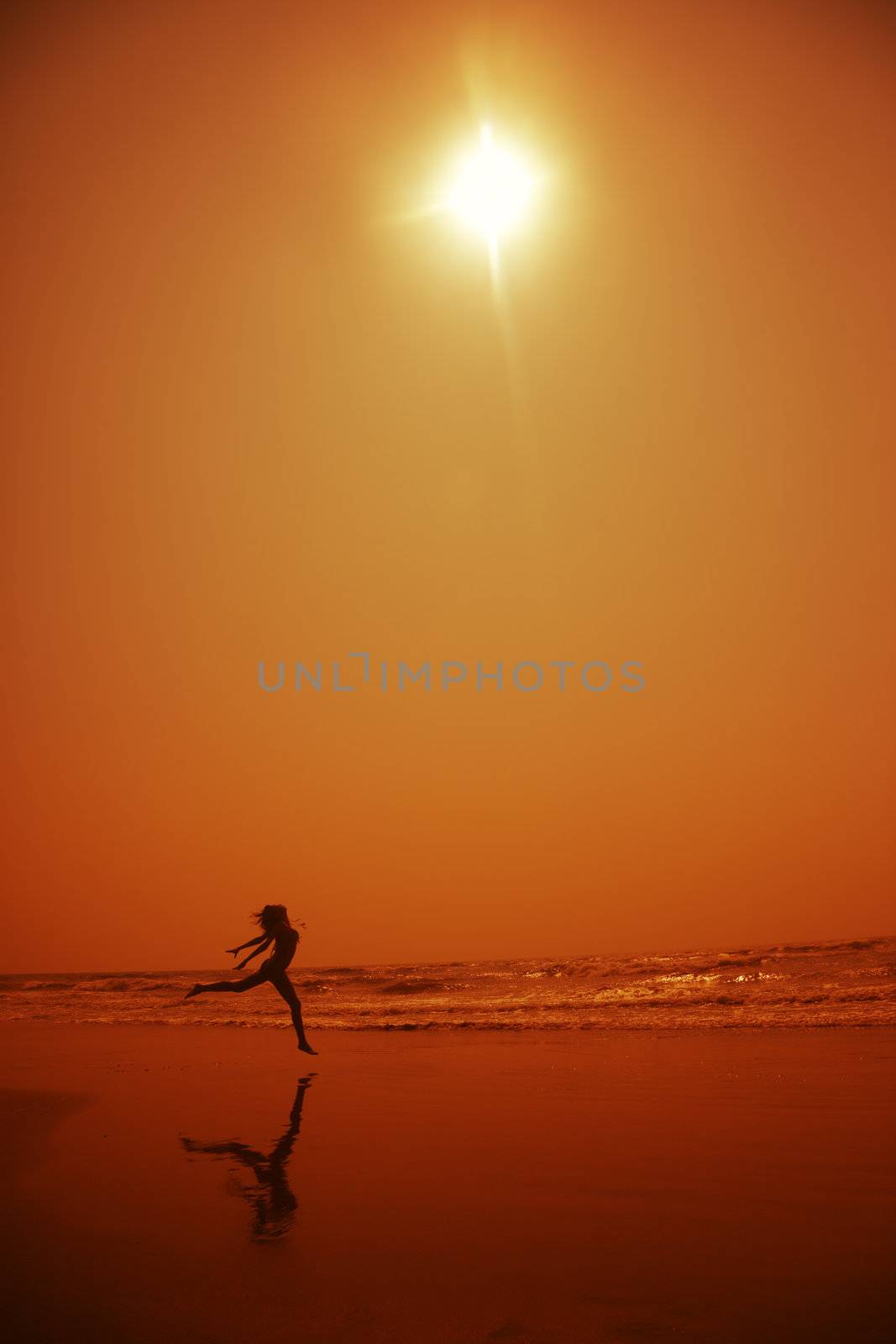 Silhouette of the lady dancing at the beach in deep dark night. Artistic orange colors toning added