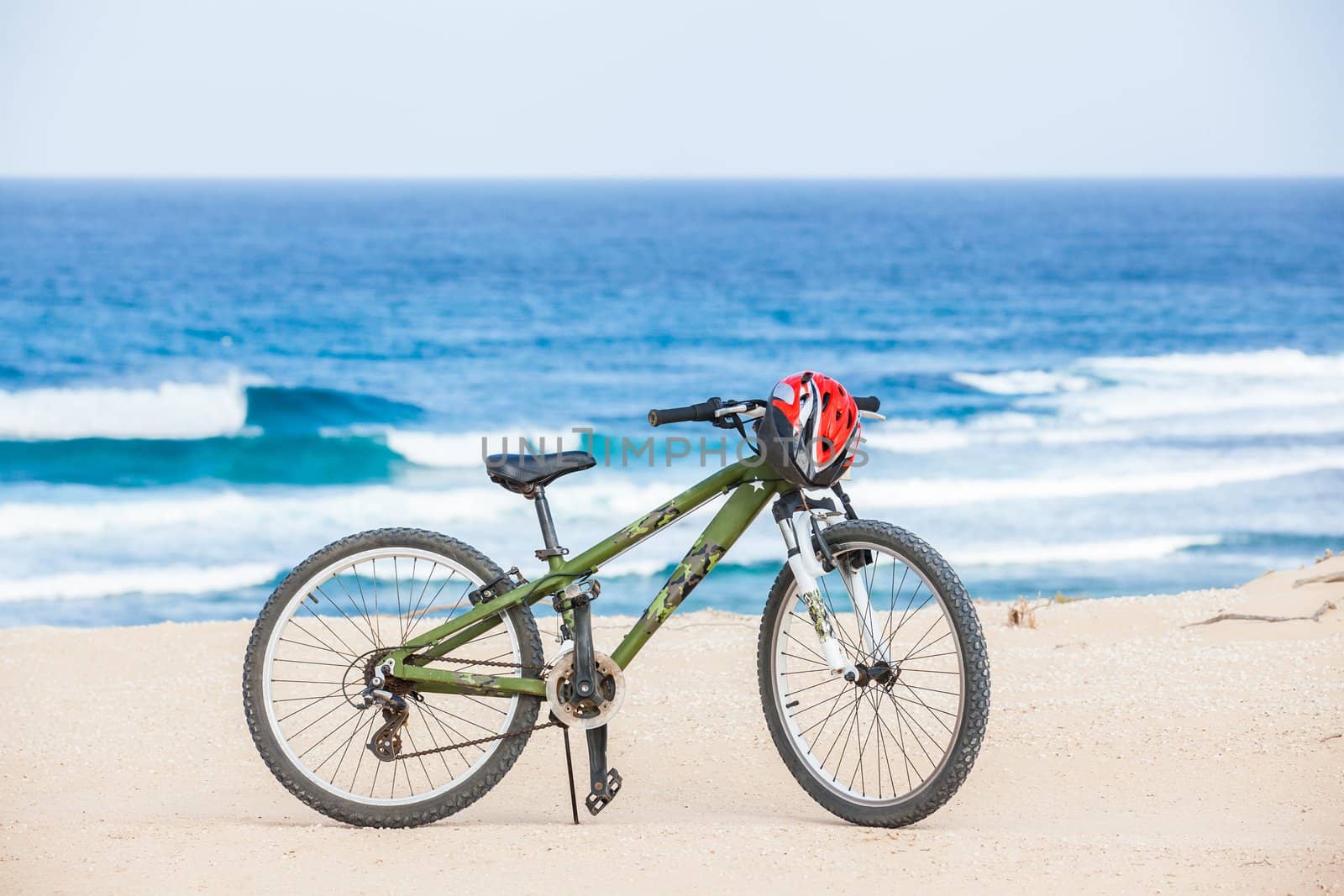 Bicycle with helmet, stand on coast line.
