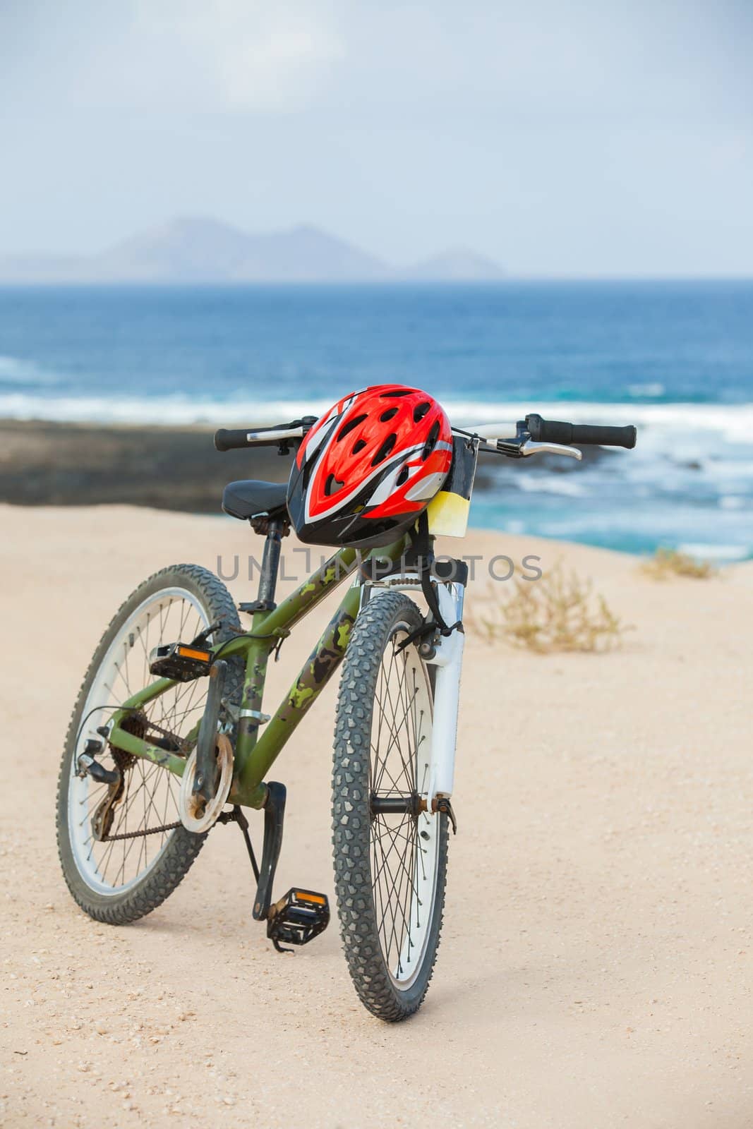Bicycle with helmet, stand on coast line. Vertical view