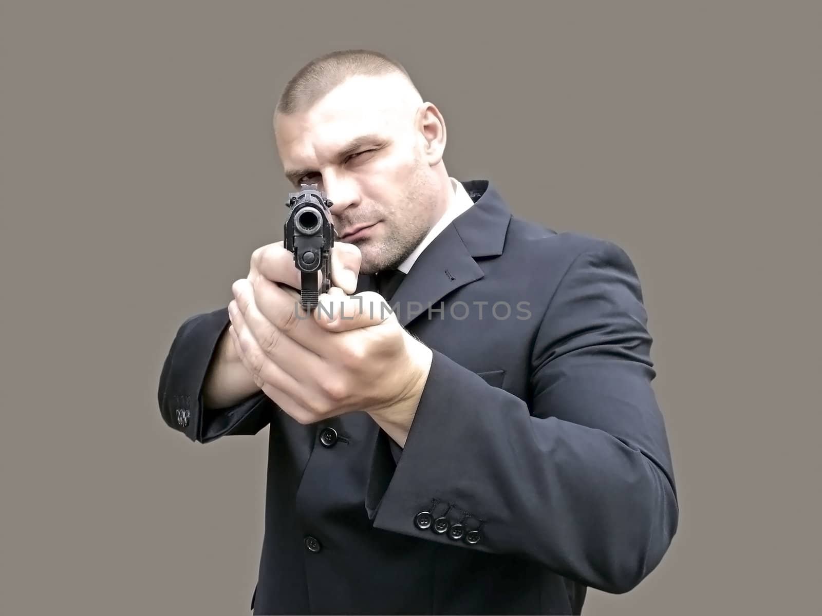                 A man with a gun in his hand, aiming for the shooting, on a gray background              