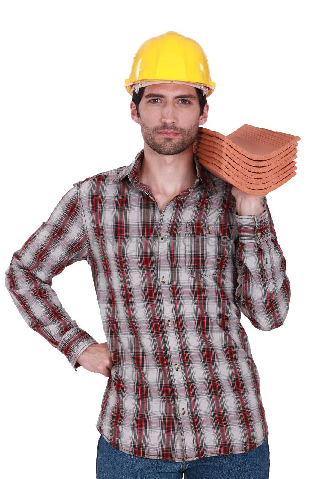 Builder holding stack of roof tiles by phovoir