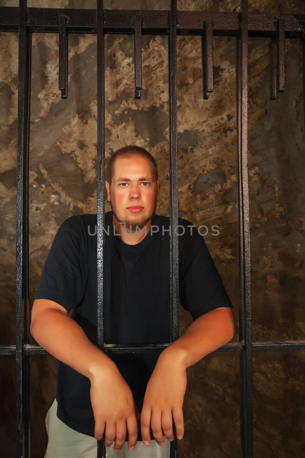 Young man looking from behind the bars
