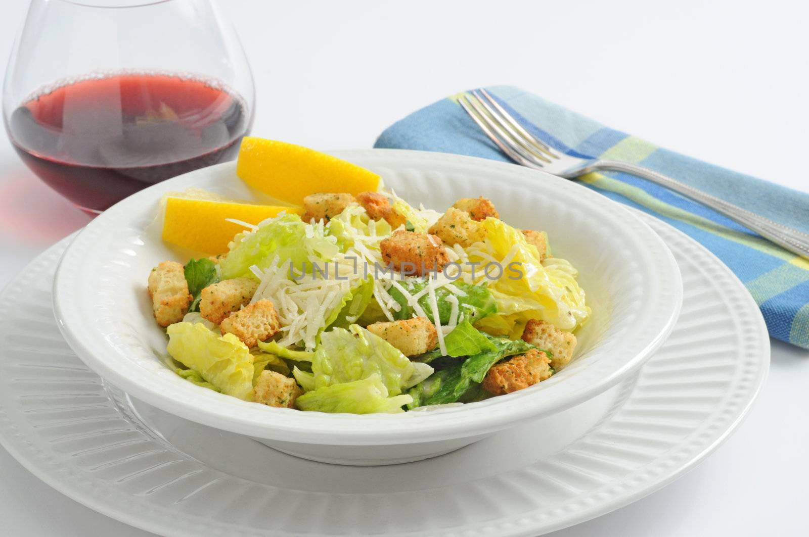 Delicious caesar salad served with red wine.