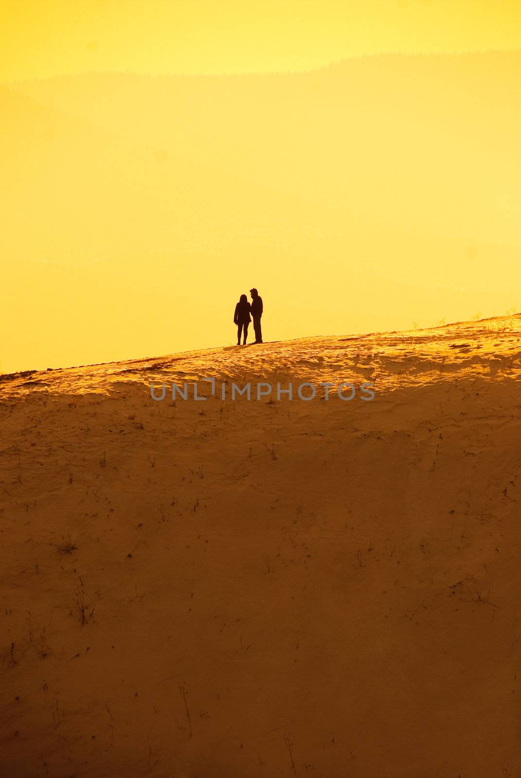 solitude, silhouettes of a man and a woman standing on the hill and holding hands