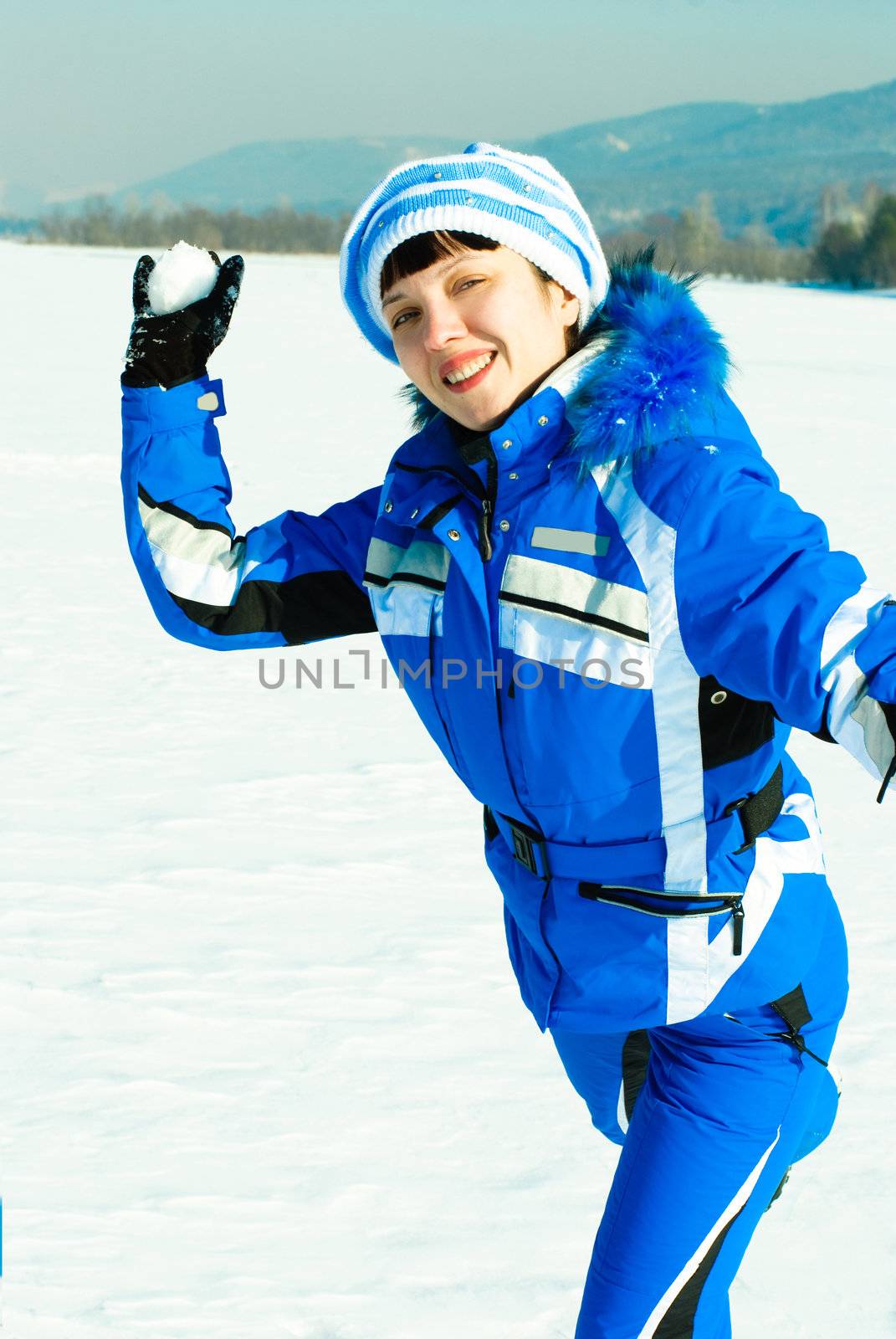 happy young woman throwing a snowball at us with a smile