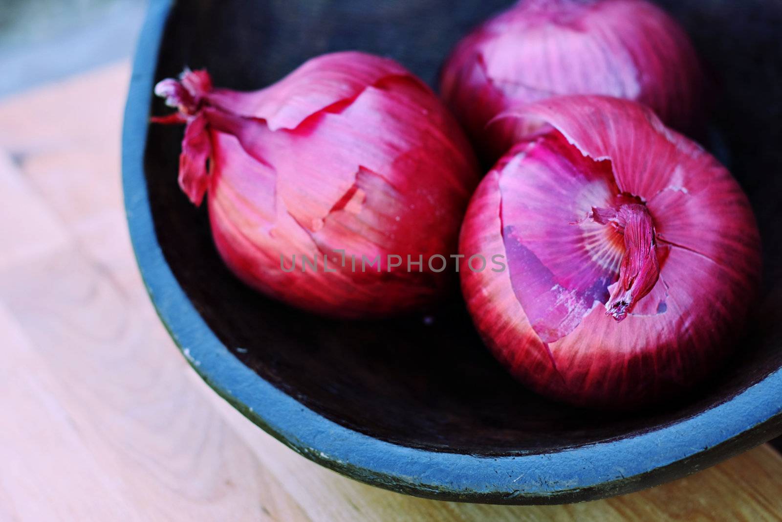 Red onions in a hand carved wooden bowl