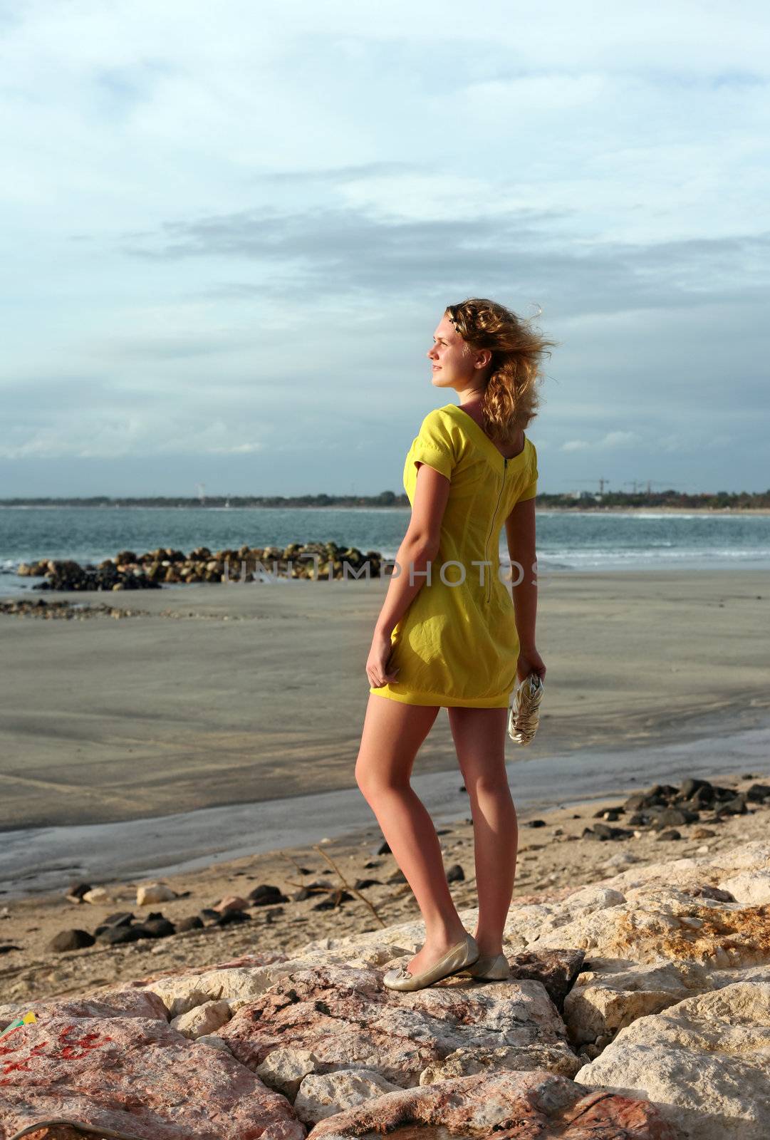 The young girl in a yellow dress on a coast of ocean