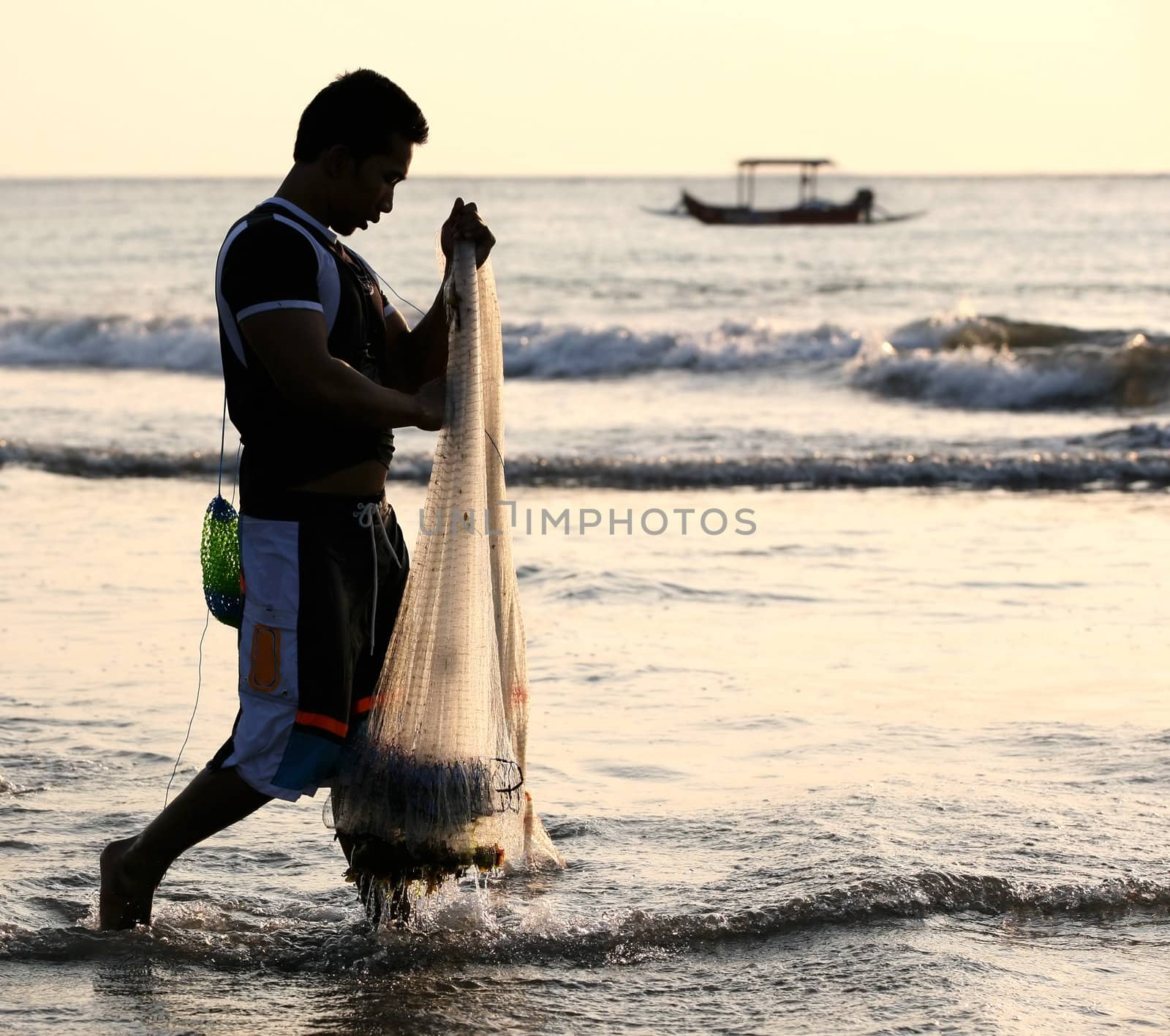 The person with a network fishing in a sunset. Indonesia. Bali