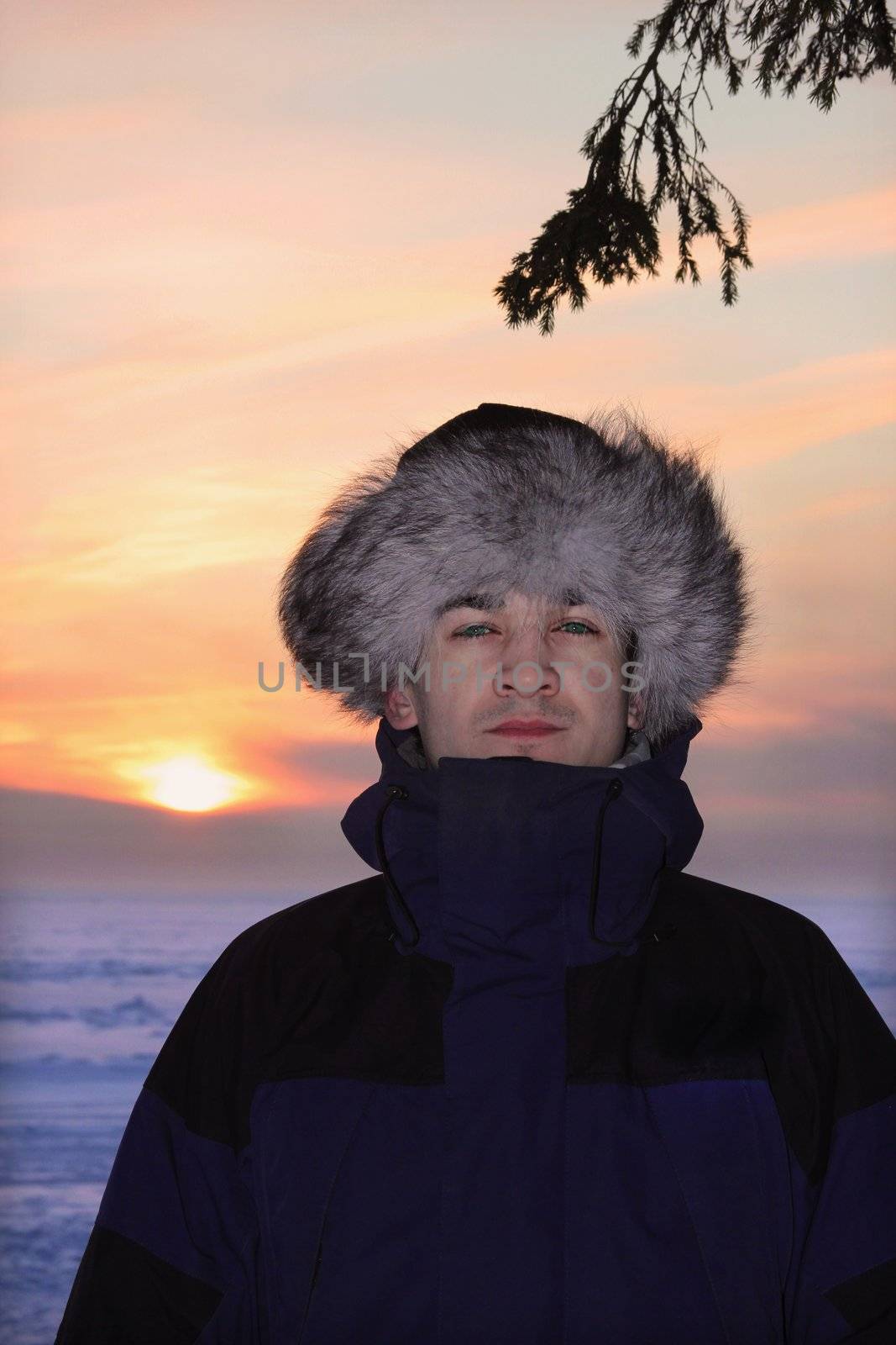 A portrait of man is in a fur cap in winter sunset