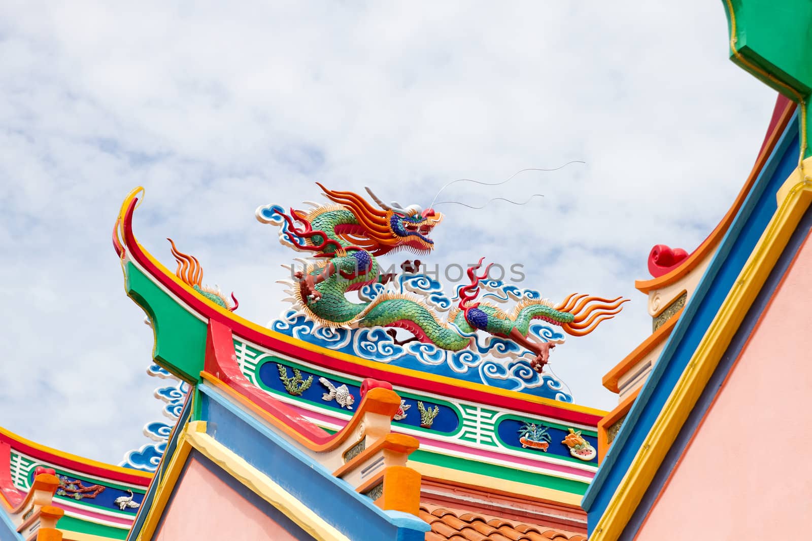 Colorful Chinese Dragon Sculpture on Temple Roof Top Against Blue Sky