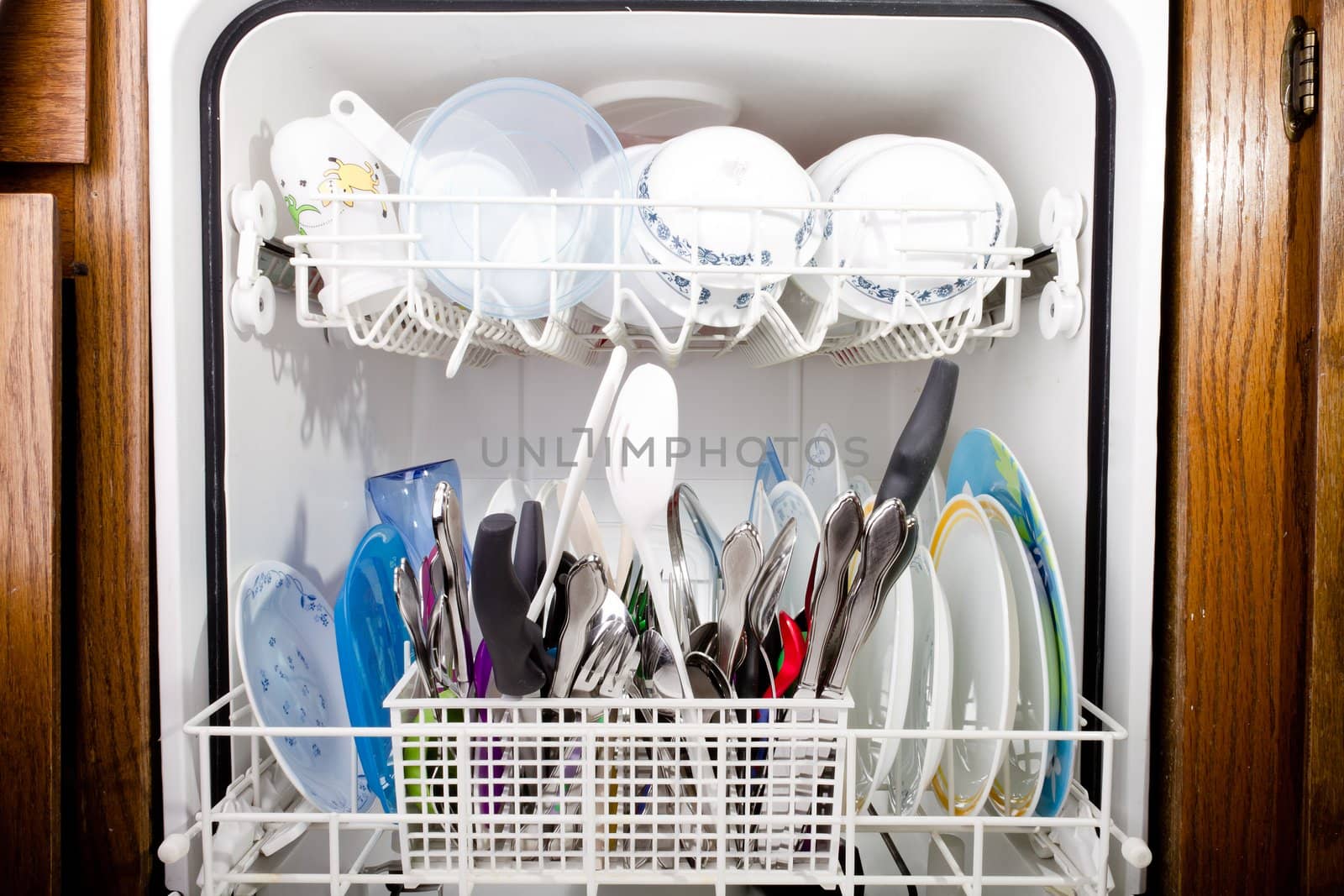 Dishwasher set set in the kitchen with wood cupboards to the side.