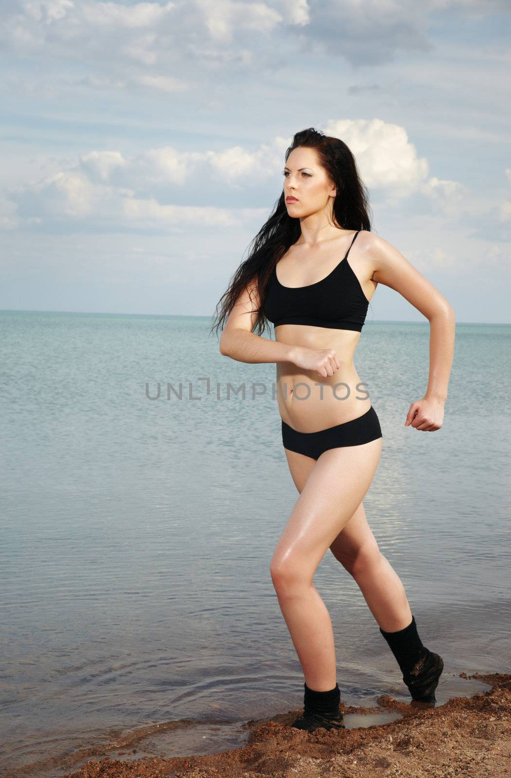 Lady outdoors with muscular figure running along the beach