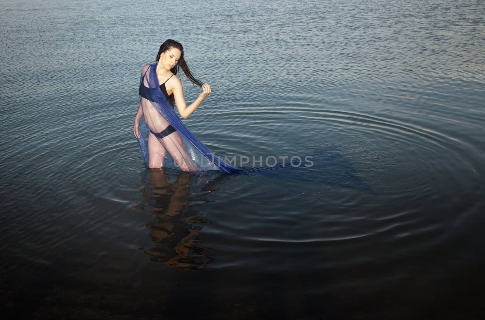 Sensual lady in bikini standing in the water. Horizontal photo