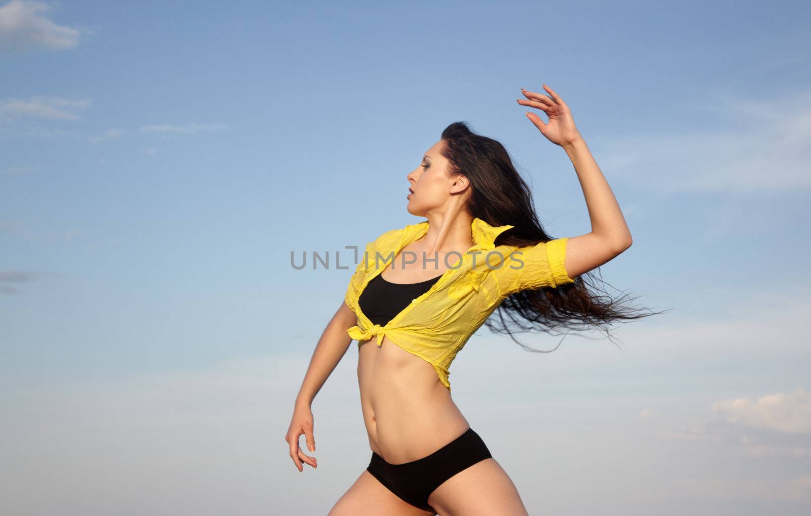 Woman doing sportive exercise outdoors on a blue sky background