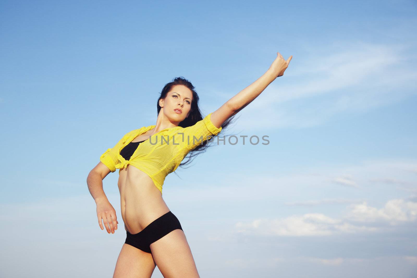 Sportive active lady outdoors doing exercise. Blue sky at the background