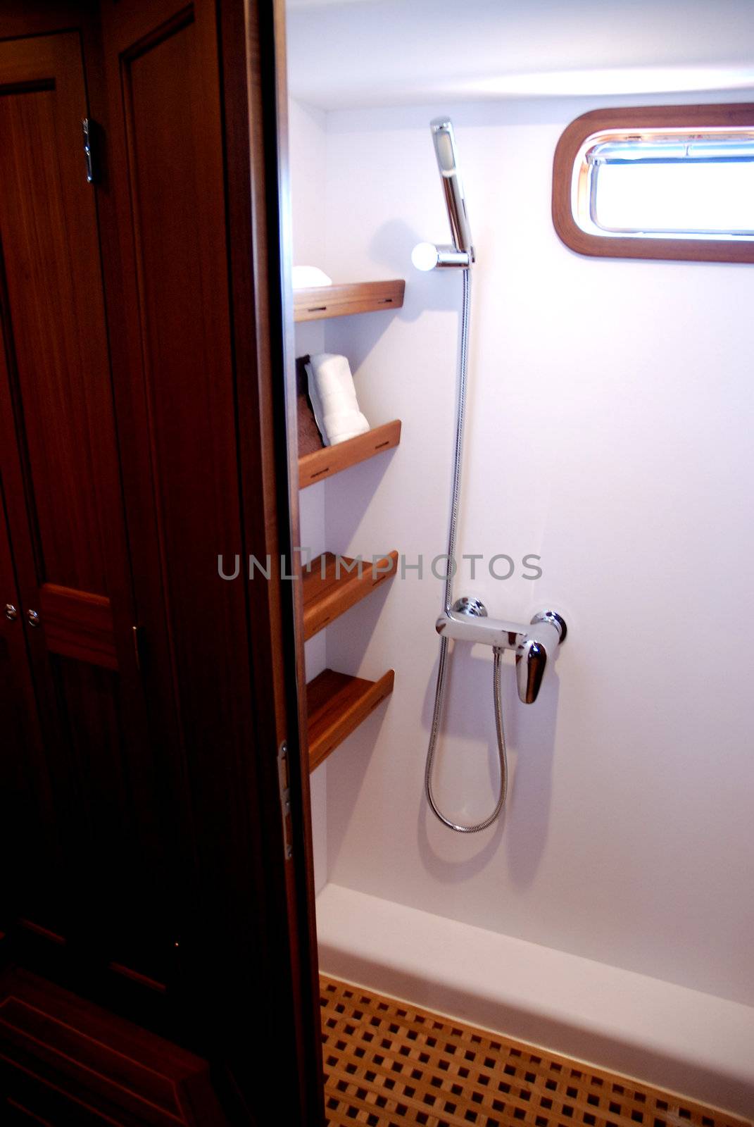 Impression of the interior of a small deluxe yacht, showing the intimate forward cabin and the heads compartment, displaying the v-shaped bunk beds, 360 degrees mahogany wood panelling, the shower and toilet compartment, including sink, and the custom built storage cabinets