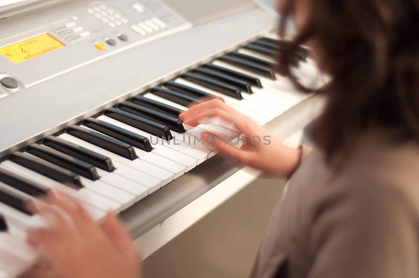 A little girl playing on an electric piano.