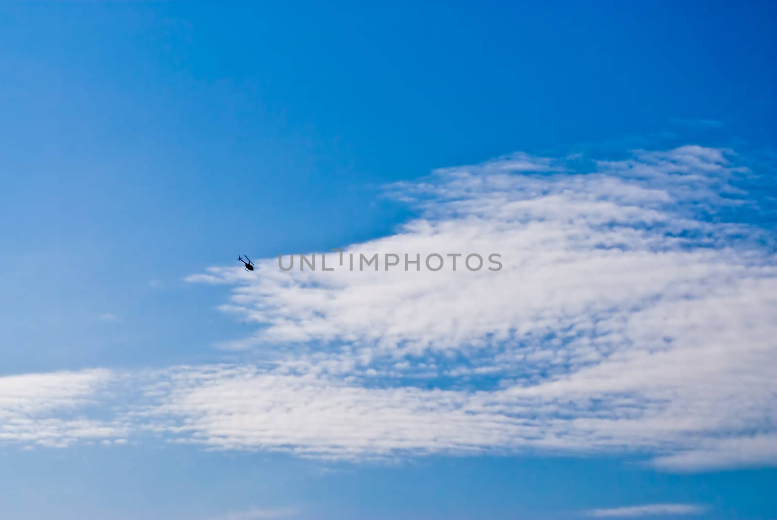 Rotary-wing aircraft in the blue cloud sky